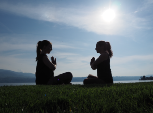 Nadine von naé yoga mit Chantal von Tada Yoga machen die Yoga-Pose Sukhasana am See in Uerikon
